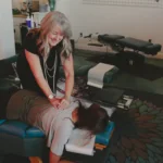 Chiropractor performing spinal adjustment on patient lying on treatment table in clinic