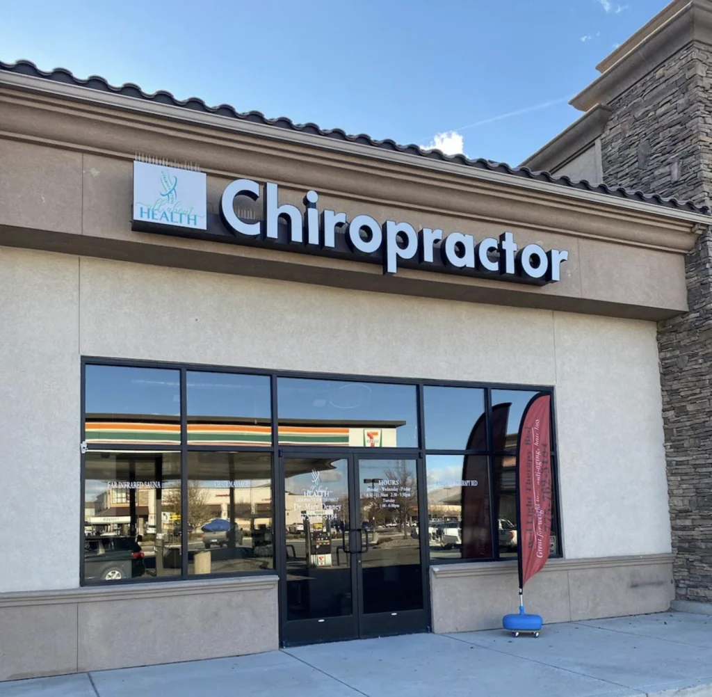 Chiropractor office storefront with large signage and glass entrance doors on a sunny day